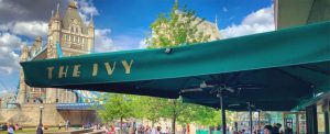 The Ivy Restaurant Tower Bridge in Central London. British brasserie with large terrace in the heart of England. Commercial parasol printed in gold to the valances.